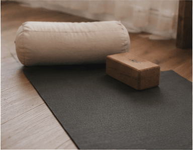 A yoga mat with bolsters and blocks arranged in soft daylight.
