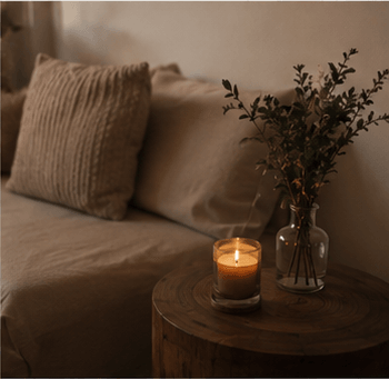 A linen-draped couch with a candle and dried flowers nearby.