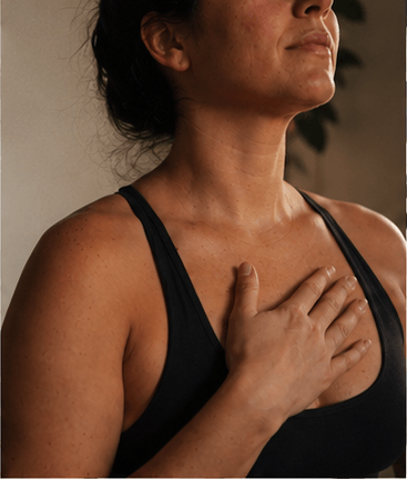 A hand resting gently on the heart in low candlelight during a breathwork session at The Black Salt Room in Dundas, Ontario.