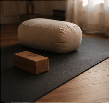 A linen bolster and wooden block on a dark studio floor.