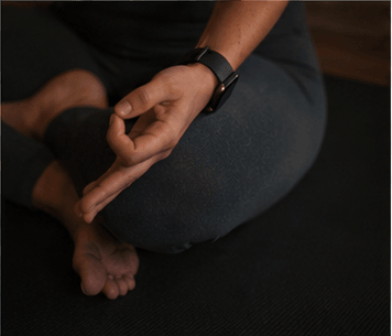 A close-up of a hand resting in a meditative mudra against the soft glow of candlelight.
